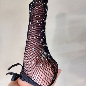 Puede incluir: Medias de red negra con pedrer&iacute;a. Las medias tienen un lazo de cinta negro en la parte superior.