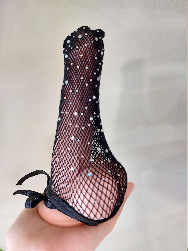 Puede incluir: Medias de red negra con pedrer&iacute;a. Las medias tienen un lazo de cinta negro en la parte superior.