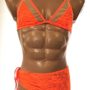 May include: A bright orange lace bra and matching skirt set. The bra has a halter style with a mesh panel in the center. The skirt is a wrap style with a tie at the side.