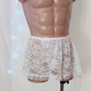 Puede incluir: Falda de encaje blanca con borde festoneado. La falda est&aacute; hecha de una tela delicada y transparente y tiene un patr&oacute;n floral.