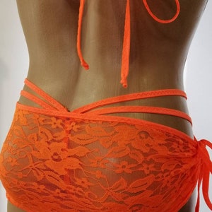 May include: Orange lace lingerie with adjustable straps and a tie at the side.