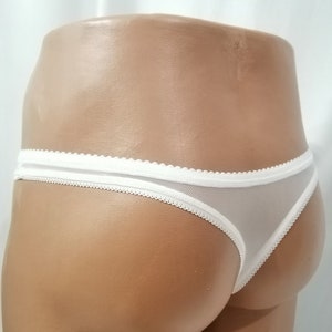 Puede incluir: Tanga de encaje blanco con un delicado borde festoneado.