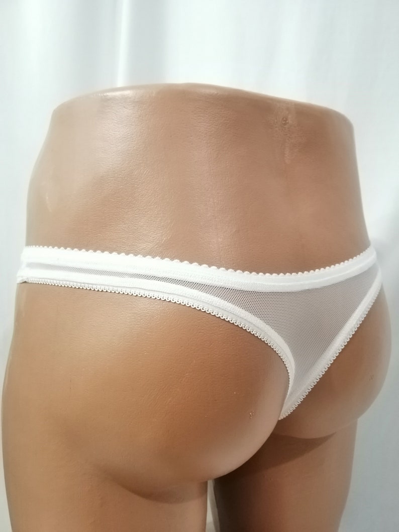 Puede incluir: Tanga de encaje blanco con un delicado borde festoneado.