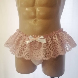 Pu&ograve; includere: Intimo in pizzo rosa con un fiocco di raso bianco. Il pizzo ha un motivo floreale.