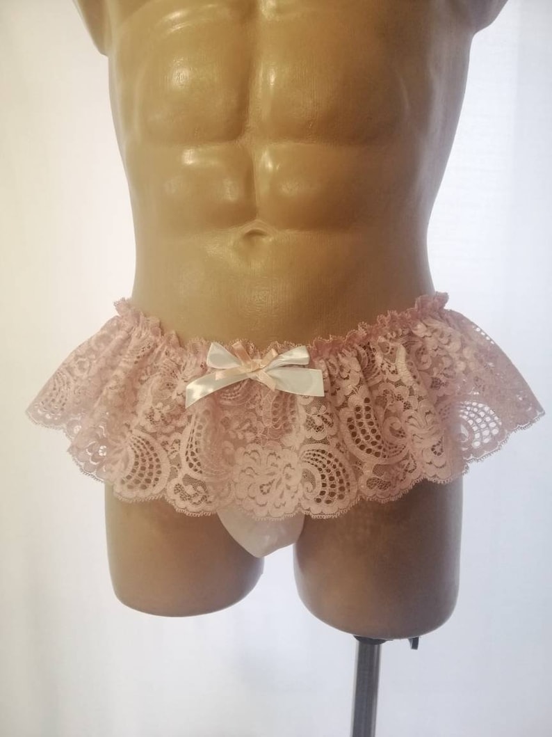 Pu&ograve; includere: Intimo in pizzo rosa con un fiocco di raso bianco. Il pizzo ha un motivo floreale.