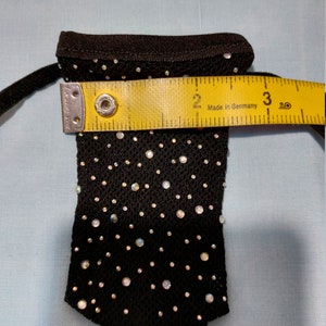 Puede incluir: Una bolsa de malla negra con cierre de cord&oacute;n, decorada con piedras de cristal iridiscentes. La bolsa mide aproximadamente 7,6 cm de ancho.