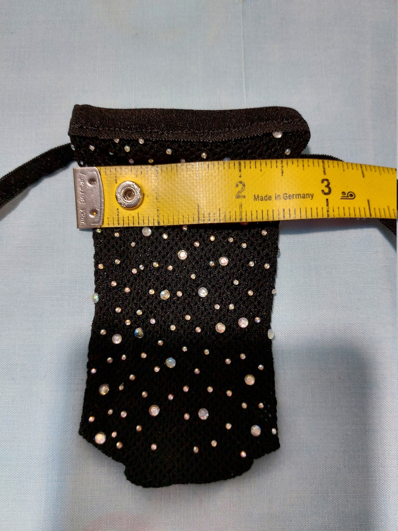 Puede incluir: Una bolsa de malla negra con cierre de cord&oacute;n, decorada con piedras de cristal iridiscentes. La bolsa mide aproximadamente 7,6 cm de ancho.