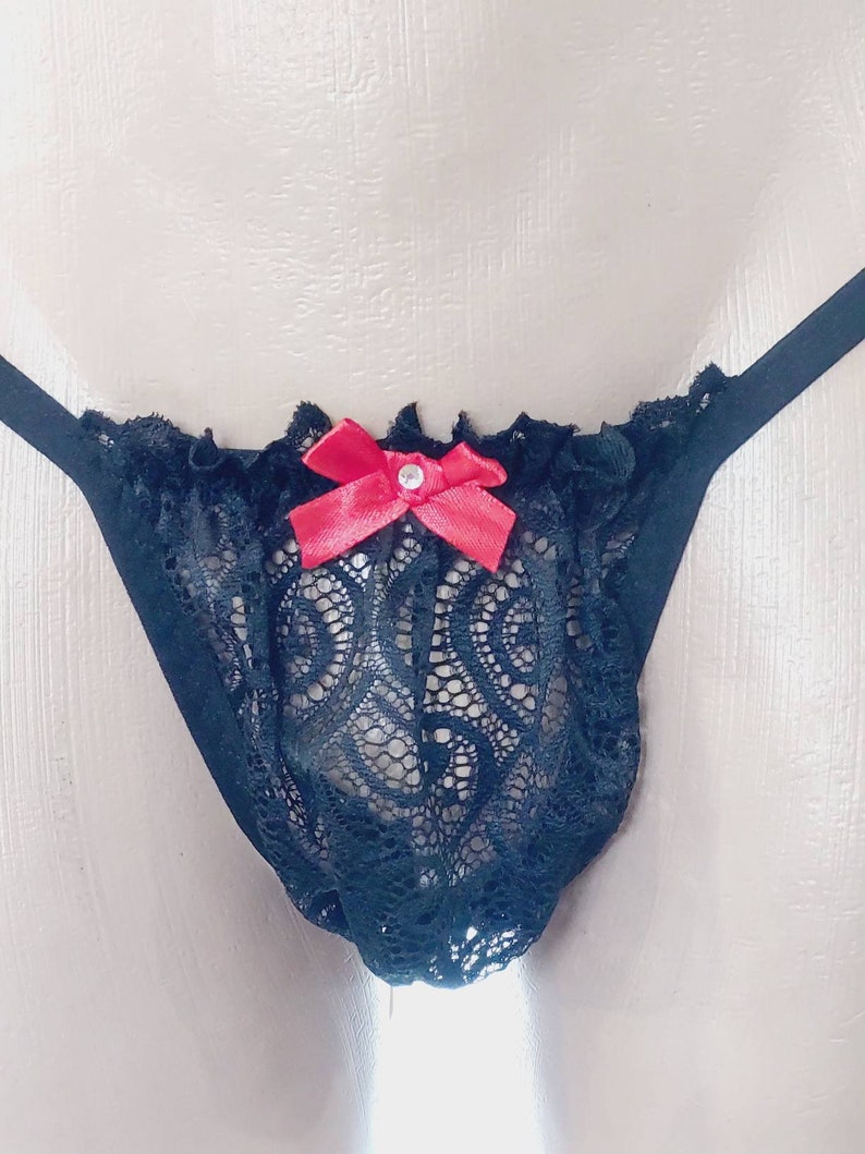 May include: Black lace underwear with a red bow and a rhinestone in the center.