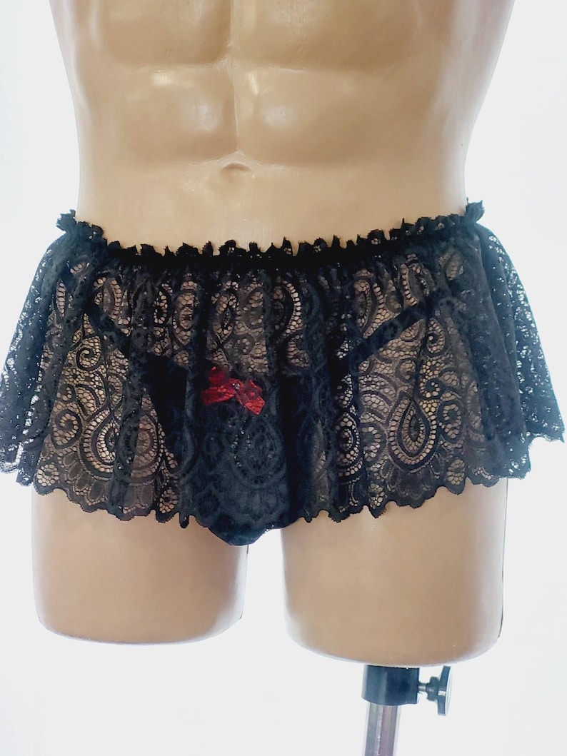 May include: Black lace lingerie with a red bow detail. The lingerie has a ruffled trim and a sheer design.