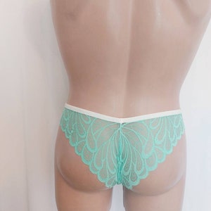 May include: Mint green lace underwear with a white trim. The underwear has a scalloped edge and a delicate floral pattern.