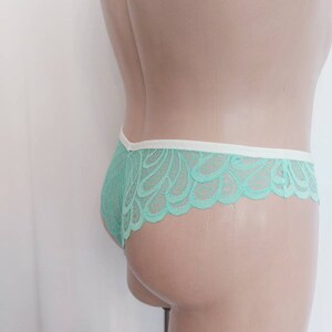 May include: Mint green lace underwear with a white trim. The underwear is shown on a mannequin.