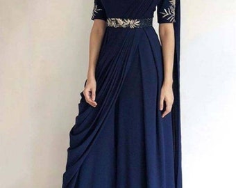 Può includere: Un abito maxi blu navy con gonna drappeggiata e cintura dorata. L'abito ha maniche corte con dettagli ricamati.