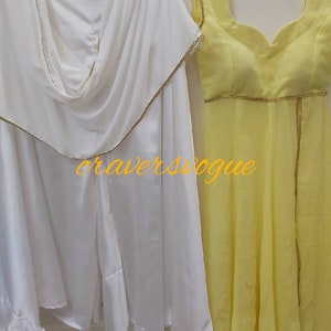 Pu&ograve; includere: Due eleganti abiti appesi a un attaccapanni. Uno &egrave; un completo bianco fluido con finiture dorate, e l'altro &egrave; un abito giallo senza maniche con finiture dorate. Il testo "craversvogue" &egrave; visibile nell'immagine.