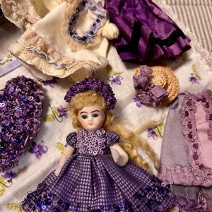 Baby Violet mignonette con una scatola di vestiti e una collezione di cartoline viola, mignonette