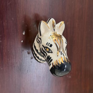 Pomo de cerámica con diseño de cebra para cajón, pintado a mano en dorado, ideal para decorar habitaciones infantiles, como un safari o para muebles con forma de animal.