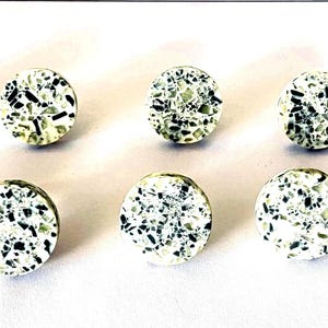 May include: Six round, white ceramic knobs with a black and white speckled pattern.