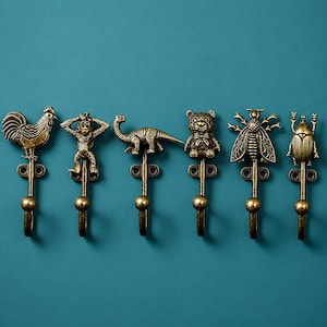 May include: A set of six antique brass-toned metal wall hooks, each featuring a distinct animal or insect figure at the top. The designs include a rooster, a monkey, a dinosaur, a teddy bear, a cicada, and a beetle, all with a ball-end hook.