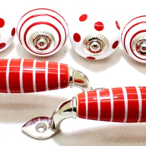 May include: Set of four red and white ceramic knobs with a striped or polka dot design and two red and white striped cabinet pulls with silver hardware.