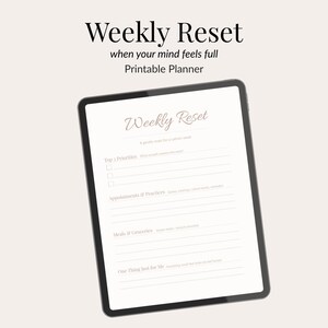 Pode incluir: Um tablet digital exibe um planejador imprimível intitulado "Weekly Reset". A tela apresenta prompts para prioridades, compromissos, refeições e autocuidado. O texto "when your mind feels full" e "Printable Planner" também são visíveis.