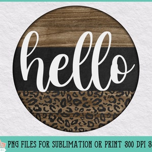 Puede incluir: Un letrero redondo de madera con un dise&ntilde;o de estampado de leopardo blanco y negro. El letrero tiene la palabra "hello" escrita en letras blancas cursivas.