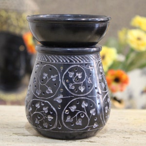 May include: Black stone oil burner with an intricate floral design. The burner has a removable top bowl for adding wax melts or essential oils.