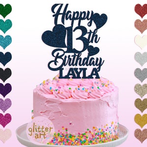 Pu&ograve; includere: Topper per torta di compleanno Happy 13th Birthday Layla con cuori glitterati e il testo "glitter art" su una torta rosa con codette colorate.