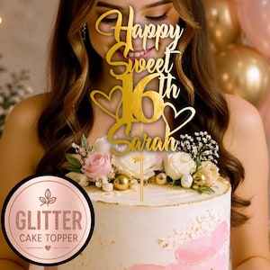 May include: A gold-coloured acrylic cake topper featuring the text Happy Sweet 16th Sarah with two heart outlines. The topper is mounted on a thin stick and is positioned atop a white frosted cake decorated with pink and white flowers.
