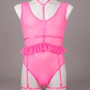 May include: A bright pink lingerie set displayed on a mannequin. The set includes a sheer bodysuit with a ruffled waist, a halter neck, and garter straps. The fabric is a vibrant, eye-catching pink.