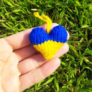 May include: A small knitted heart in the colors of the Ukrainian flag, blue and yellow, with a loop for hanging.