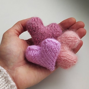 Pode incluir: Três corações de malha em tons de rosa e rosa claro. Os corações são feitos à mão e têm uma textura macia e felpuda.