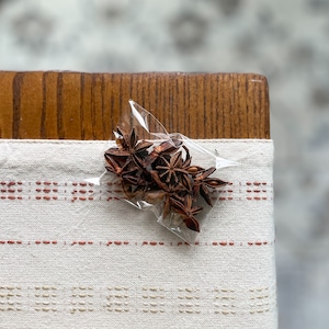 May include: A close-up of a small plastic bag filled with dried star anise, a common spice used in cooking.