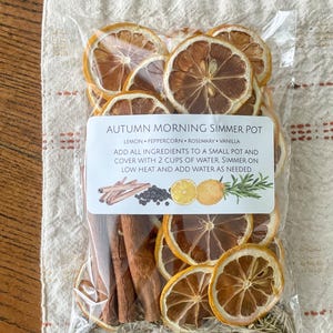 May include: A clear plastic bag filled with dried lemon slices, cinnamon sticks, peppercorns, and rosemary. The label reads "Autumn Morning Simmer Pot" with instructions. The ingredients are for a simmer pot.