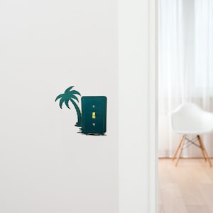 May include: A teal light switch cover with a palm tree silhouette design. The switch is off and the toggle is gold.