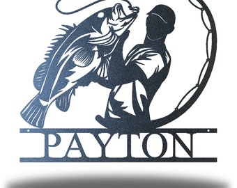 May include: A metal silhouette of a person holding a fish with a fishing rod. The silhouette is in a dark blue color and the name "PAYTON" is written below the silhouette.