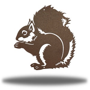 May include: A brown metal squirrel silhouette, featuring a detailed design with white accents. The squirrel is depicted in a seated position, holding something in its paws. The artwork is suitable for outdoor or indoor decor.