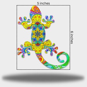 May include: A decorative lizard with a detailed, patterned design. The lizard is approximately 12.7 cm wide and 15.2 cm long, featuring a vibrant mix of yellow, blue, red, and green. The design includes floral and geometric elements.