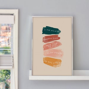 May include: A beige poster with colourful brushstrokes and the text "IN THE WILD OF CHANGING THINGS MAKE TIME FOR WHAT HELPS YOU SLOW DOWN AND BREATHE"
