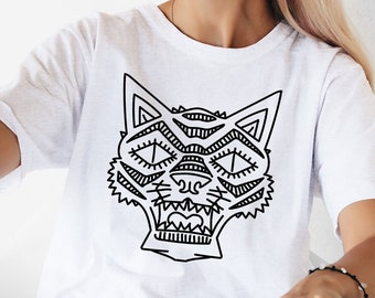 May include: A woman wearing a white t-shirt with a black and white graphic of a stylized cat face. She is holding a black cat in her left hand and wearing black cat ear headbands.
