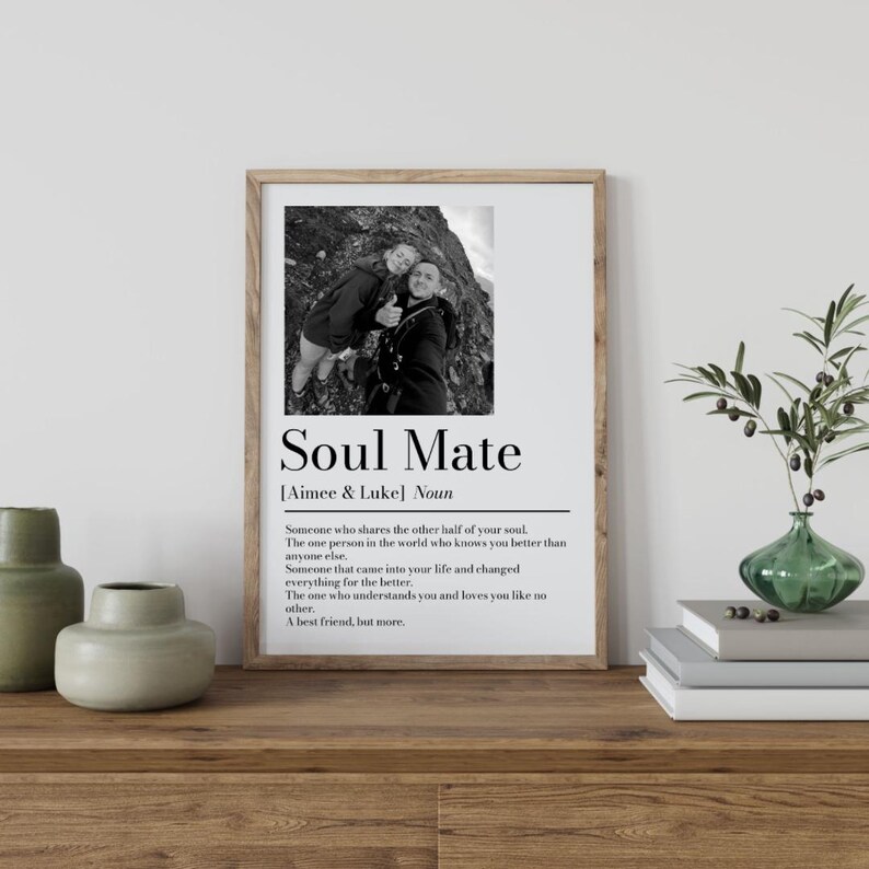 May include: A framed print with the words "Soul Mate" and a definition, along with a black and white photo of two people. The print is in a wooden frame and sits on a wooden surface.