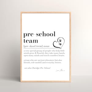 K&ouml;nnte beinhalten: Gerahmter Druck mit den schwarzen Worten &bdquo;pre-school team&ldquo;. Die Definition des Begriffs steht unter dem Titel. Ein Herz mit Handabdr&uuml;cken befindet sich auf der rechten Seite. Der Rahmen ist hellbraun.