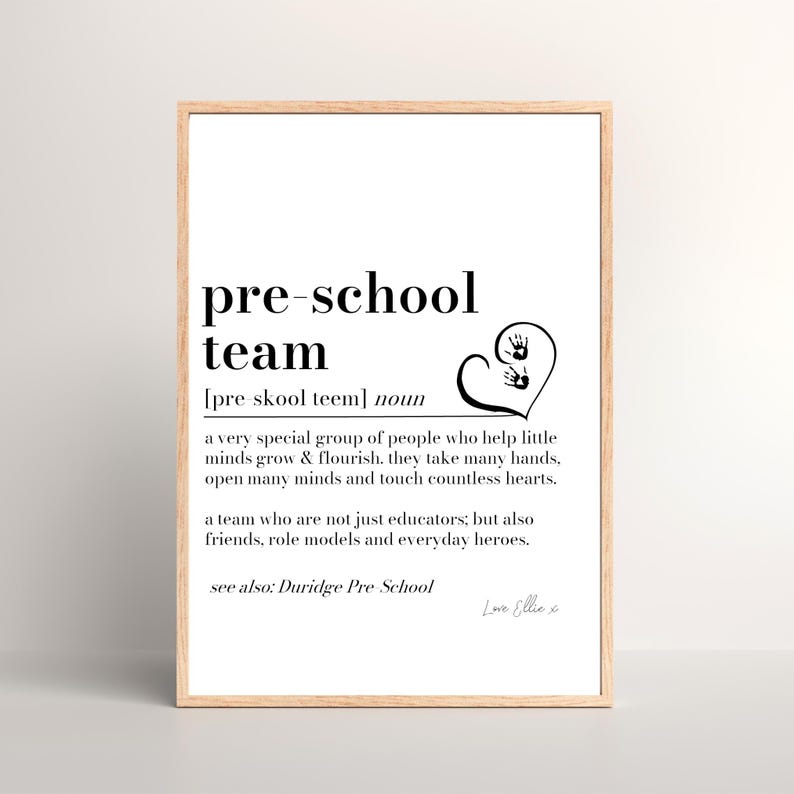 K&ouml;nnte beinhalten: Gerahmter Druck mit den schwarzen Worten &bdquo;pre-school team&ldquo;. Die Definition des Begriffs steht unter dem Titel. Ein Herz mit Handabdr&uuml;cken befindet sich auf der rechten Seite. Der Rahmen ist hellbraun.