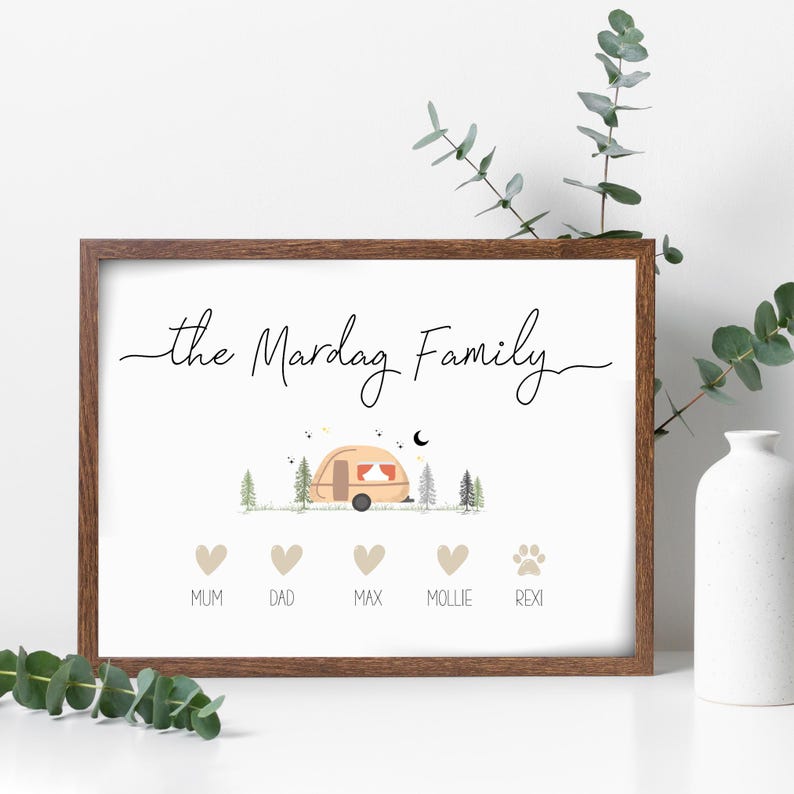 May include: A white framed print with the text "the Mardag Family" in black cursive script. A cartoon illustration of a camper van in a forest setting is above the text. Below the illustration are five icons: four hearts and a paw print. The hearts are labelled "Mum", "Dad", "Max", and "Mollie". The paw print is labelled "Rexi".