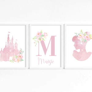 May include: Three watercolor prints featuring a pink castle, a pink letter M with floral accents, and a pink silhouette of a woman with a floral crown. The letter M is followed by the name "Maisie".