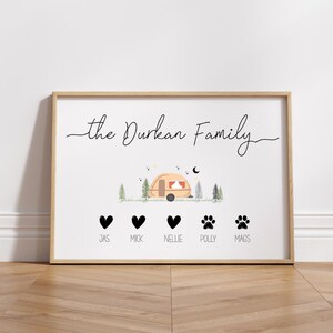 May include: A white framed print with the text "the Durkan Family" and a cartoon illustration of a camper van in a woodland setting. Below the camper van are five black icons, two hearts and three paw prints, with the names "Jas", "Mick", "Nellie", "Polly", and "Mags" written underneath.