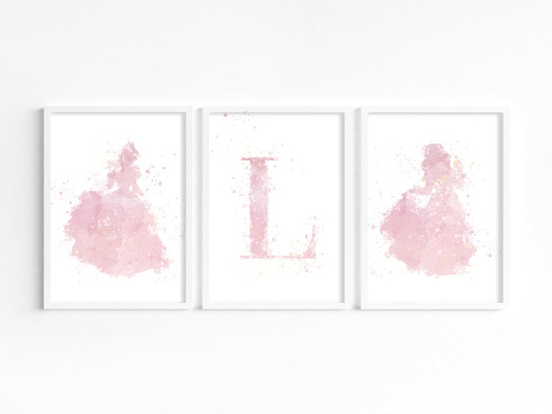 May include: Three framed prints with a pink watercolor design. The left and right prints feature a silhouette of a princess in a ball gown. The center print features the letter "L" in pink watercolor.