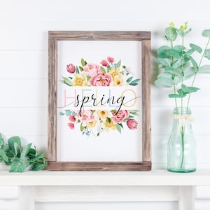 May include: A framed print with a watercolor illustration of a bouquet of pink, yellow, and white flowers. The text "hello spring" is written in black script across the flowers.