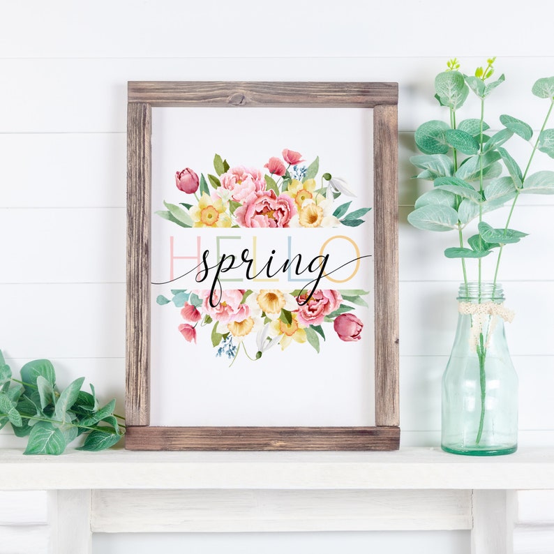 May include: A framed print with a watercolor illustration of a bouquet of pink, yellow, and white flowers. The text "hello spring" is written in black script across the flowers.