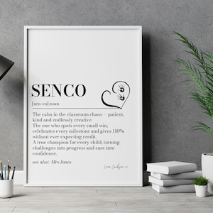 Könnte beinhalten: Ein weiß gerahmter Kunstdruck mit der schwarzen Definition von SENCO, die eine geduldige und kreative Person beschreibt. Das Design enthält ein Herz mit zwei kleinen Handabdrücken und den handschriftlichen Text Love Jackson x.