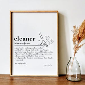 Könnte beinhalten: Gerahmter Druck mit der Definition von "cleaner" in schwarzem Text. Die Definition enthält eine Zeichnung eines Mopps und einer Hand mit einem Putztuch. Der Druck befindet sich in einem Holzrahmen und wird auf einer Holzoberfläche angezeigt.