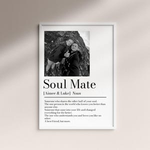 May include: A framed black and white print featuring a photograph of two people smiling. The print includes the text "Soul Mate" with a definition below, and the names "Aimee & Luke". The print is in a white frame.